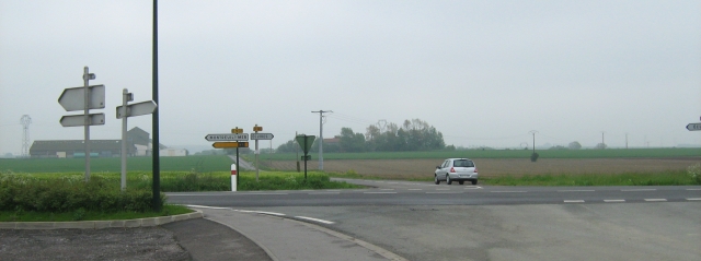broad flat farmland with a crossroad and signs in france